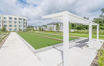 A park with a green lawn and a white pavilion with benches